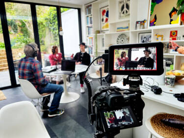 A BTS photo of Dom Salmon's Z 6II camera set up with his cage. For the Nikon magazine. Caption can read: Here Dom (check shirt) is recording a podcast with Kerry from wellness consultancy, Together We Breathe and Matt from experimental organisers. Realm at the London shoot location Sourcey) and is using his Z6ii in tandem with the very popular Atomos Ninja V to record the Pod for YouTube. The Ninja is great for cheap, high volume storage recording and a big bright monitor, one less thing thing to worry about! Shot is taken by an Iphone to show the use of a cage